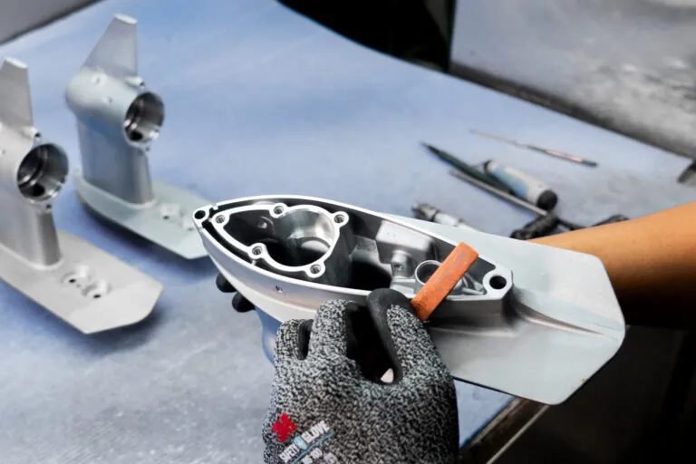 Manual deburring and final surface finish inspection of a precision aluminum die cast marine component after CNC machining.