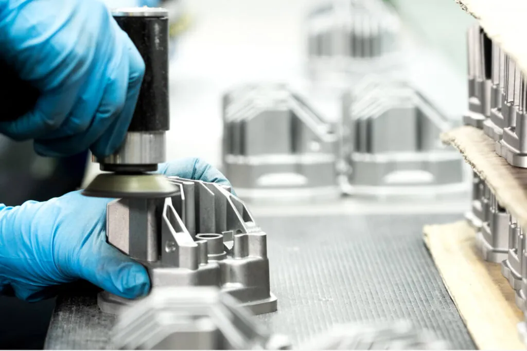 JoinCast technician performing manual polishing and surface preparation on aluminum die cast lighting components to ensure flawless finish quality.