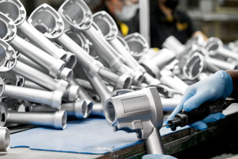 Skilled technician performing manual deburring and precision surface preparation on an aluminum pneumatic tool handle prior to coating.