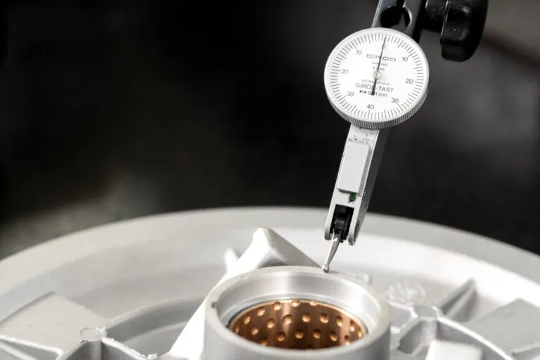 High-precision dial indicator measuring critical bores of an aluminum die casting to ensure strict adherence to ±0.01mm tolerances.