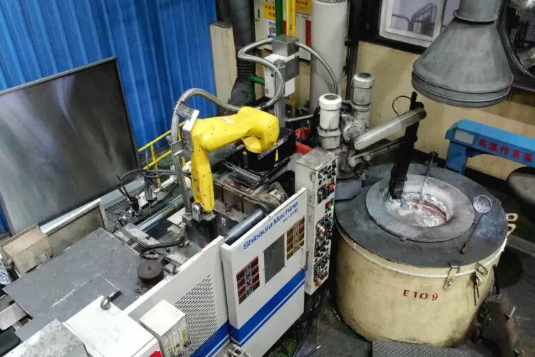 High-pressure Shibaura die casting machine integrated with a 6-axis robotic arm for automated ladling and precision metal injection.